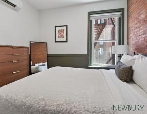 a bedroom with a large white bed and a window at 304 Newbury Street by Thatch in Boston
