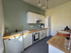 a kitchen with white cabinets and a sink at La Maisonnette de Fontaine - Au calme avec jardin in Fontaine-sous-Jouy +16 photos