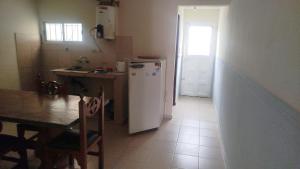 a kitchen with a table and a white refrigerator at ruta 8 suites in Santa Catalina