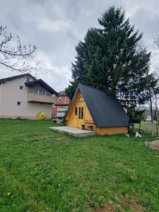 a wooden cabin in a yard next to a house at Auto kamp Runolist in Rožaje