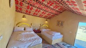 two beds in a room with a red ceiling at Fayoum Desert Camp in Qaryat Ḩātim aţ Ţāʼī