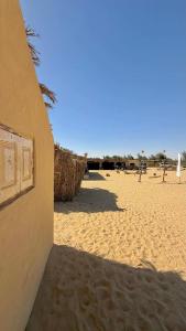 a building on the beach with a sandy beach at Fayoum Desert Camp in Qaryat Ḩātim aţ Ţāʼī