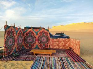 a blanket sitting on top of a rug in the desert at Fayoum Desert Camp in Qaryat Ḩātim aţ Ţāʼī