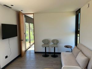 a living room with a couch and two stools at Tiny House en parcela de Puerto Varas in Puerto Varas