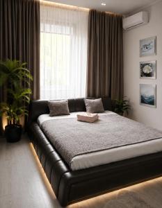 a black bed in a room with a large window at Central Apartment Facing the Cathedral in Chişinău