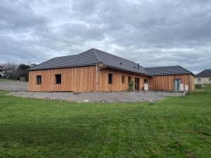a large wooden building in a field of grass at Villa Bois d'Argent in Lagraulière
