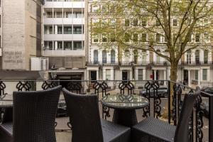 a patio with a table and chairs on a balcony at Beaufort House - Knightsbridge in London