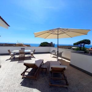 a patio with tables and chairs and an umbrella at Surf and Windsurfer House Anzio in Anzio