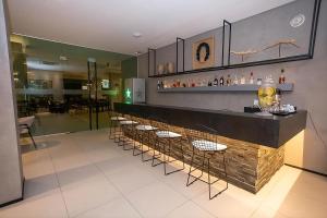 a bar with a row of stools in a restaurant at Acqua Prime Maceió Ponta Verde in Maceió