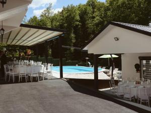 a pool with white tables and chairs next to a building at Villa Tea - Private Pool Villa, Slatina in Laktaši