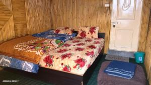 a small bedroom with two beds and a door at Chauhan bambo house in Joshīmath