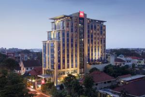 ein hohes Gebäude mit einem roten Schild darüber in der Unterkunft Hotel Ibis Semarang Simpang Lima in Semarang