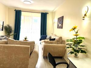 a living room with two couches and a plant at Savana Abode-Nakuru CBD in Nakuru