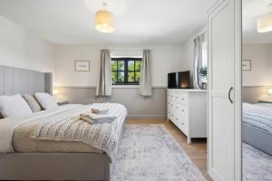 a bedroom with a bed and a dresser and a window at Five Acres Cottage in Rickmansworth