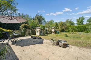 a patio with an umbrella and a playground at Five Acres Cottage in Rickmansworth