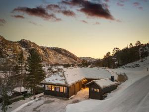 a house covered in snow with the lights on at Large modern cabin from 2023 for rent in Dirdal
