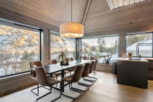 a dining room with a table and chairs and large windows at Large modern cabin from 2023 for rent in Dirdal