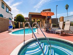 a swimming pool with an umbrella next to a house at Rancho San Diego Inn & Suites in El Cajon