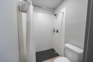 a white bathroom with a shower with a toilet at Hummingbird Hotel in Goodlettsville