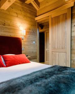 a bedroom with wooden walls and a bed with red pillows at CHALET EVEREST Les CHALETS D'HINOUKA SERRE CHEVALIER-CHANTEMERLE 200 m des pistes in Saint-Chaffrey