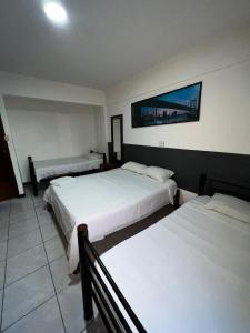 a bedroom with three beds and a picture on the wall at Ibiza Hostel Suites in Santa Cruz de la Sierra