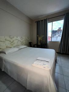 a large white bed in a room with a window at Ibiza Hostel Suites in Santa Cruz de la Sierra