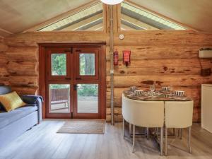a dining room with a table and a blue couch at Owl Valley Cabin in Oswestry