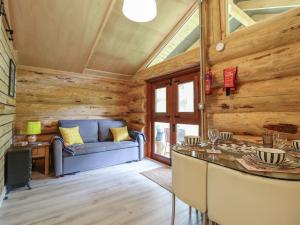 a living room with wooden walls and a blue couch at Owl Valley Cabin in Oswestry +16 photos