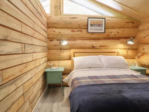 a bedroom with a bed in a wooden cabin at Owl Valley Cabin in Oswestry