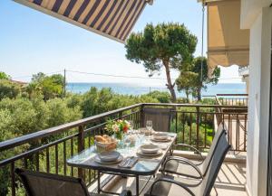a table on a balcony with a view of the ocean at Golden Beach Apartment in Nea Moudania