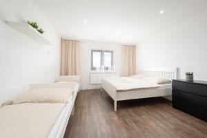 a white bedroom with two beds and a dresser at Dům Pavlov in Pavlov