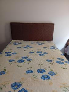 a bed with a blanket with blue flowers on it at Casa da Helenice in São Roque de Minas +9 photos