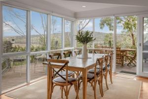 a dining room with a table and chairs and windows at The Ridge House Panoramic views in Aireys Inlet