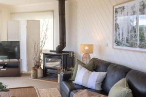 a living room with a black leather couch and a fireplace at The Ridge House Panoramic views in Aireys Inlet