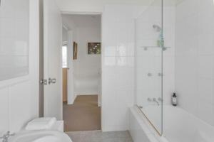 a white bathroom with a shower and a toilet at The Ridge House Panoramic views in Aireys Inlet +46 photos