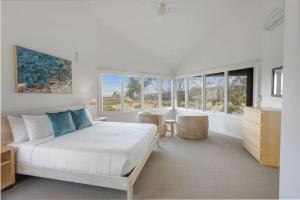 a bedroom with a large white bed and windows at The Ridge House Panoramic views in Aireys Inlet