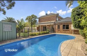 a house with a swimming pool in front of a house at MawsonLakes Lake view Villa in Mawson Lakes