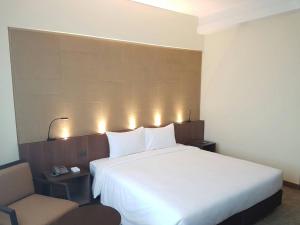 a bedroom with a large white bed and a chair at Louis Tavern Hotel in Bangkok