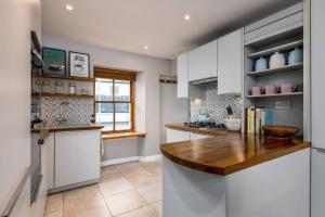 a kitchen with white cabinets and a wooden counter top at Pear Tree Cottage, Dunblane in Dunblane