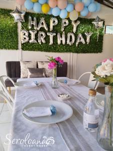 a table with a happy birthday sign and flowers on it at Seroloana Guest House in Rustenburg +61 photos
