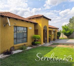 a yellow house with a lawn in front of it at Seroloana Guest House in Rustenburg