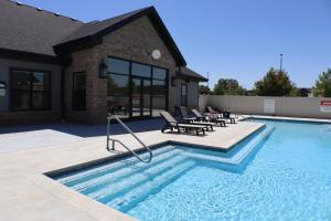 a swimming pool with chairs and a house at The Drop Inn NWA Basecamp in Rogers
