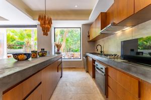 a kitchen with wooden cabinets and a large counter top at Elements Rituals Beachfront Bahia Soliman Tulum in Tulum