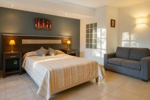 a bedroom with a bed and a couch and a chair at Blumenau Apart Hotel in Villa General Belgrano