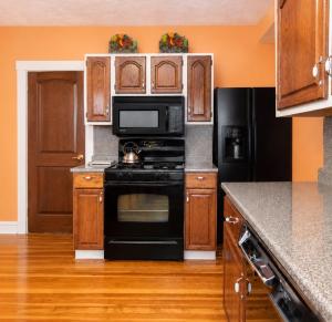 a kitchen with black appliances and wooden cabinets at Victorian Condo in Boston