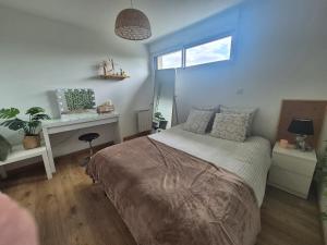 a bedroom with a bed with a desk and a window at Cocon moderne et chaleureux in Craon
