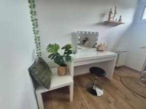 a desk with a mirror and a stool with a plant at Cocon moderne et chaleureux in Craon +2 photos