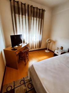 a bedroom with a bed and a desk with a television at Flor da Providência in Viseu