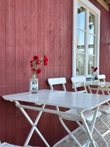 a white table and chairs against a red wall at Sandvik Gästhamn & Camping in Kökar