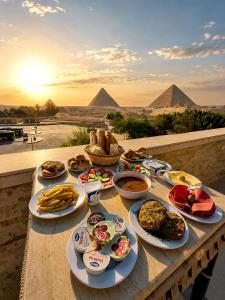 a table full of food with pyramids in the background at Cacillion Pyramids View in Cairo +37 photos